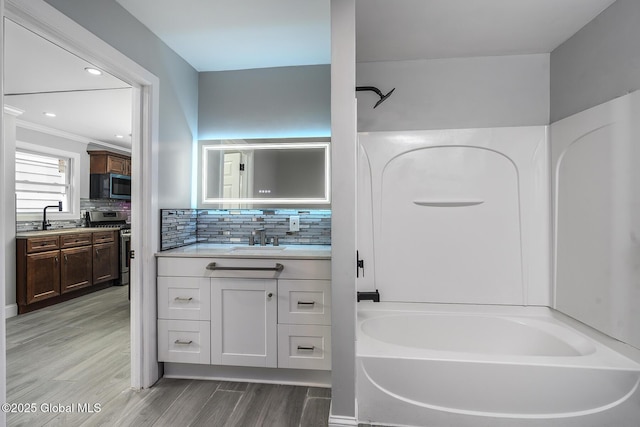 full bath with two vanities, wood finished floors, tasteful backsplash, and ornamental molding