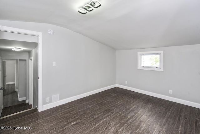 additional living space featuring dark wood finished floors, vaulted ceiling, and baseboards