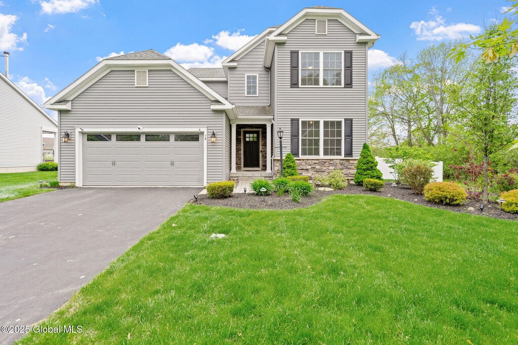 18 Newell Ln, Bethlehem, NY 12077 - traditional-style home with driveway, a front yard, an attached garage, stone siding, and a shingled roof
