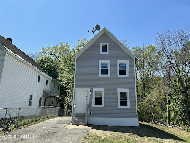 rear view of property with entry steps and fence