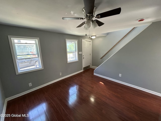 empty room with baseboards, wood finished floors, and a ceiling fan