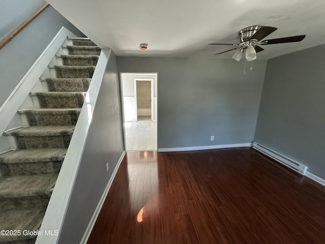 stairs featuring a baseboard heating unit, wood finished floors, baseboards, and ceiling fan
