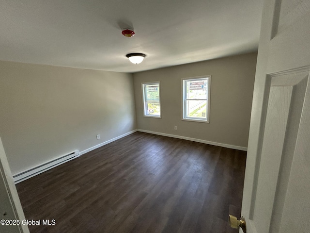 spare room with a baseboard radiator, dark wood-type flooring, and baseboards