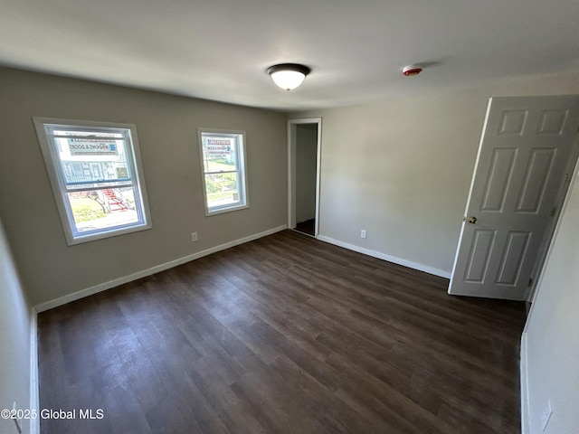 empty room with dark wood-style floors and baseboards