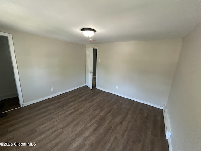 spare room with dark wood-type flooring and baseboards