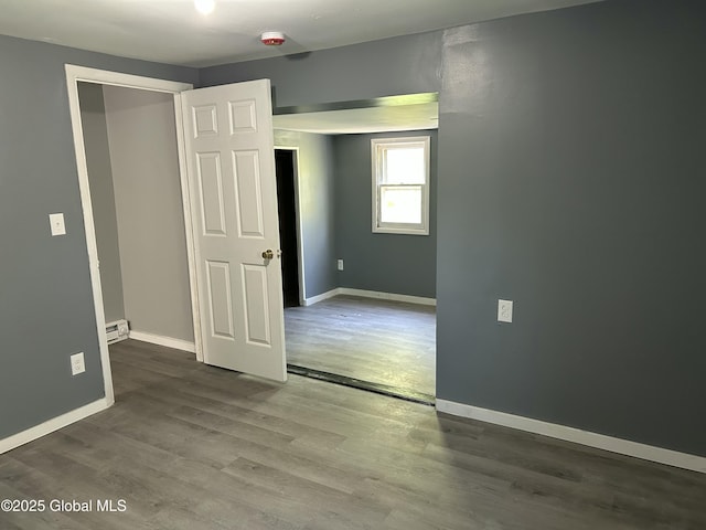 spare room with wood finished floors, baseboards, a smoke detector, and a baseboard radiator