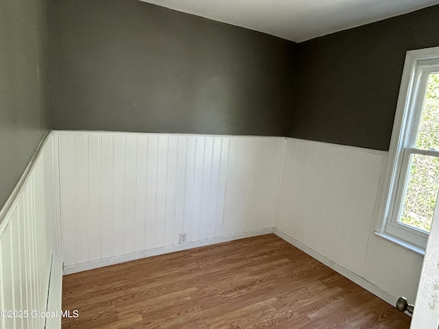 spare room with a wainscoted wall and wood finished floors
