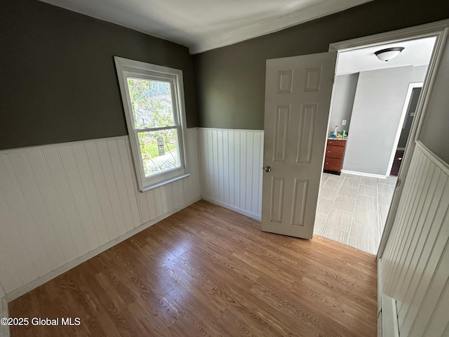 empty room with a wainscoted wall and wood finished floors