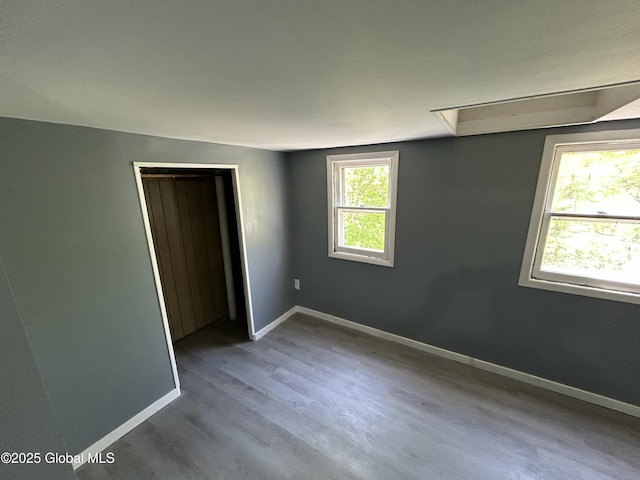 unfurnished bedroom with baseboards, wood finished floors, and a closet