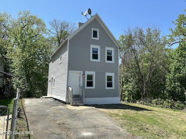 back of property with entry steps and a lawn