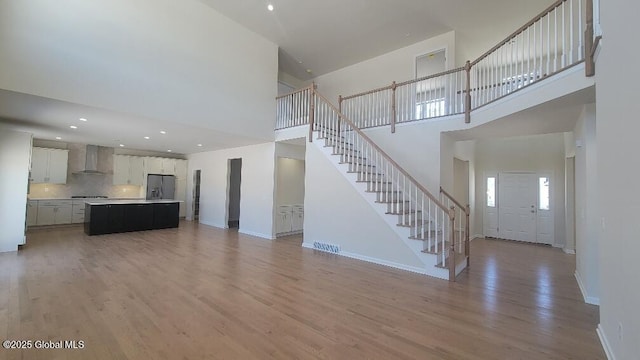 35 Sally St, Halfmoon, NY 12118 - unfurnished living room featuring a high ceiling, stairway, light wood finished floors, baseboards, and recessed lighting