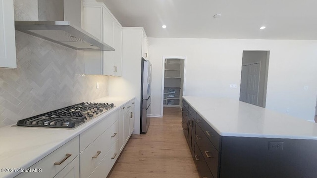 35 Sally St, Halfmoon, NY 12118 - kitchen with stainless steel appliances, wall chimney exhaust hood, white cabinetry, light wood-style flooring, and tasteful backsplash