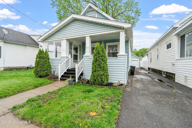 shotgun-style home with a front yard, an outbuilding, covered porch, and a detached garage