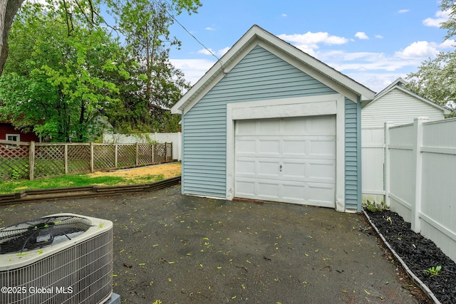 detached garage with cooling unit, fence, and asphalt driveway
