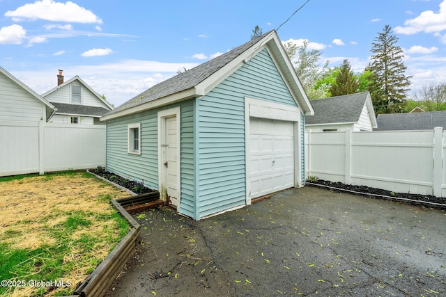 detached garage featuring fence and driveway