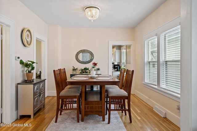 dining room with light wood-style floors, a chandelier, and baseboards