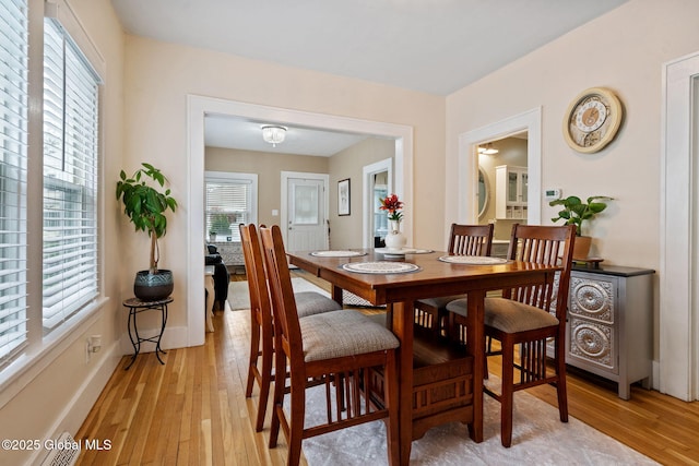 dining space with light wood-type flooring and baseboards
