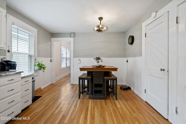 dining area featuring a wainscoted wall and light wood-style flooring