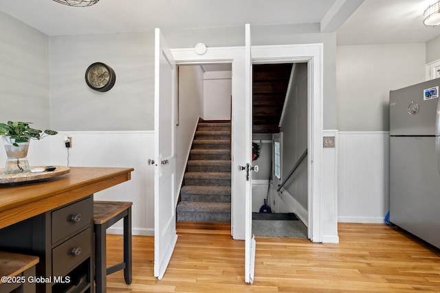 stairway featuring wood finished floors and wainscoting
