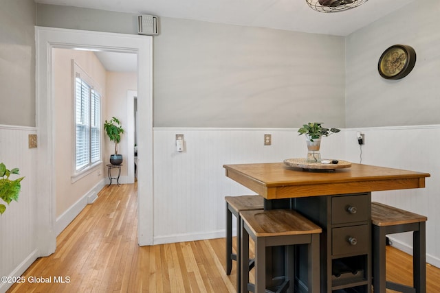 dining room featuring a wainscoted wall, light wood-style flooring, and baseboards