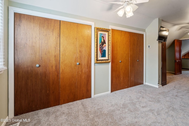 unfurnished bedroom featuring carpet, two closets, baseboards, and ceiling fan