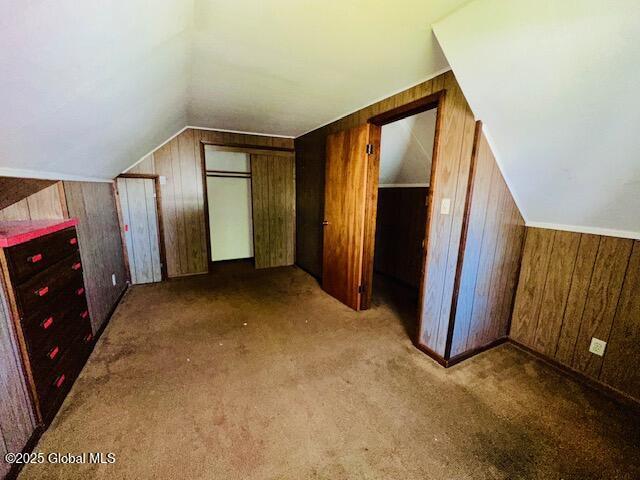 bonus room featuring wooden walls, vaulted ceiling, and carpet