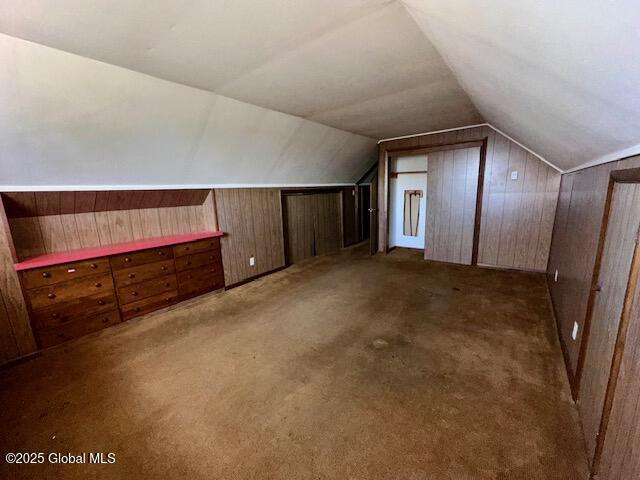 bonus room with vaulted ceiling, wooden walls, and carpet flooring