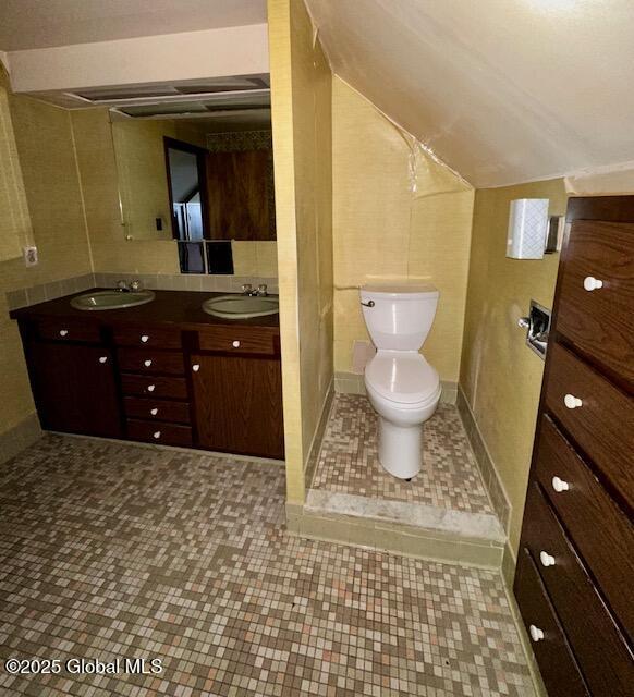 bathroom with toilet, double vanity, tile patterned flooring, and lofted ceiling