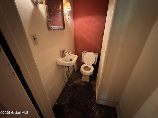 bathroom with toilet, a sink, and tile patterned floors