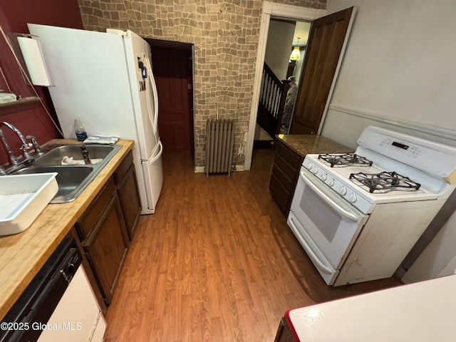 kitchen featuring white appliances, radiator heating unit, light wood-style flooring, a sink, and wooden counters