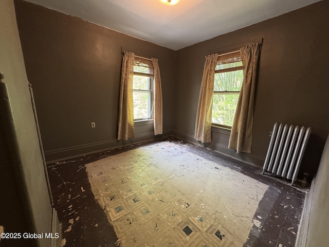 unfurnished room featuring radiator, healthy amount of natural light, and baseboards