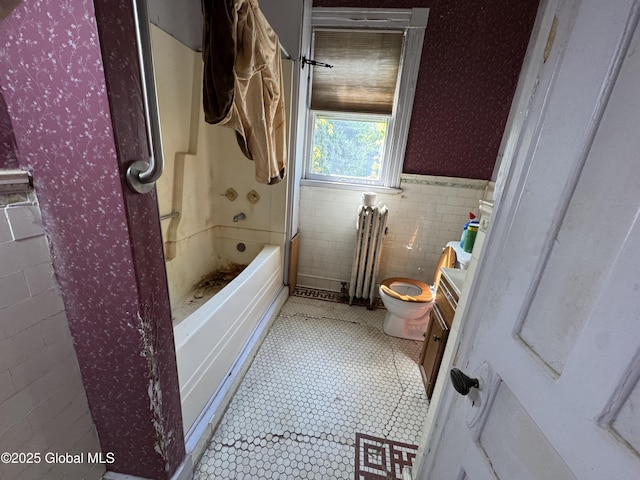 bathroom with radiator, a wainscoted wall, toilet, tile patterned flooring, and tile walls
