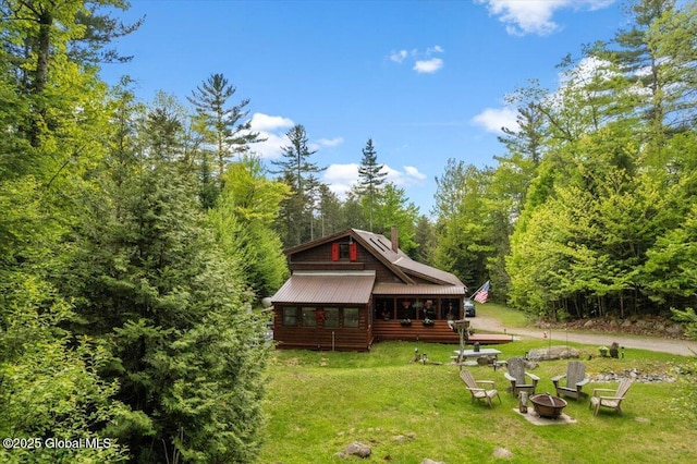 152 Sweenie Fields Rd, Schroon Lake, NY 12870 - back of property featuring a fire pit, a lawn, a forest view, a chimney, and metal roof