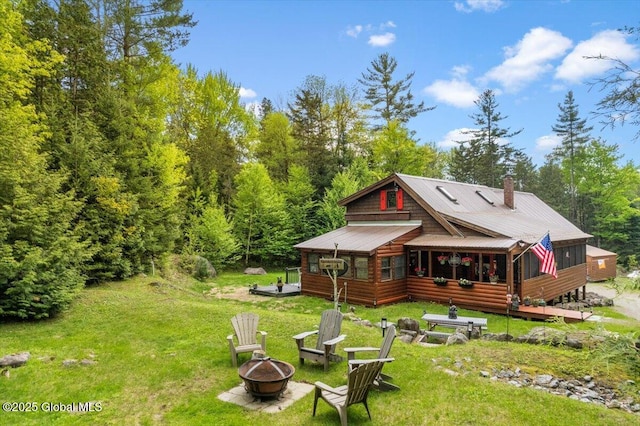152 Sweenie Fields Rd, Schroon Lake, NY 12870 - back of house with a fire pit, a lawn, a deck, metal roof, and a chimney