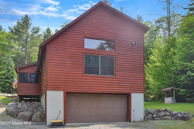 152 Sweenie Fields Rd, Schroon Lake, NY 12870 - view of property exterior with a garage, log veneer siding, stucco siding, and driveway