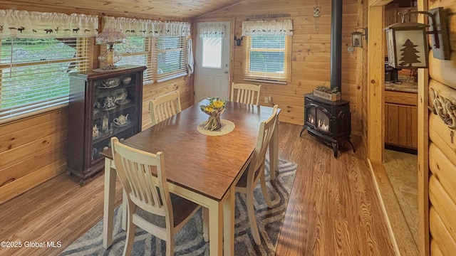 152 Sweenie Fields Rd, Schroon Lake, NY 12870 - dining space featuring a wood stove, light wood-type flooring, vaulted ceiling, and wooden walls