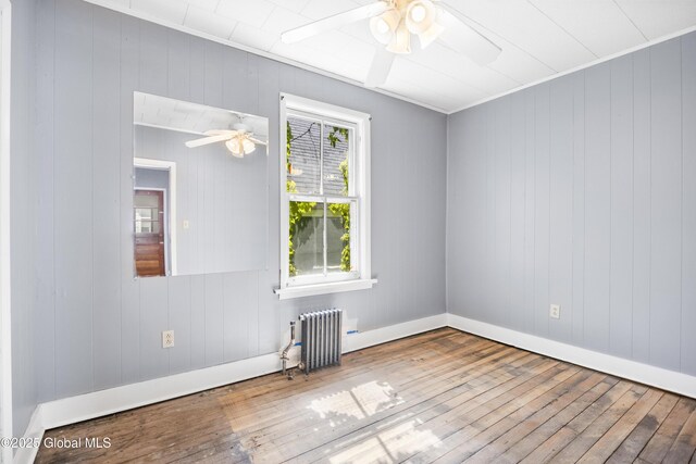 9 Archibald St, Colonie, NY 12189 - spare room featuring ceiling fan, radiator, hardwood / wood-style floors, baseboards, and wooden walls