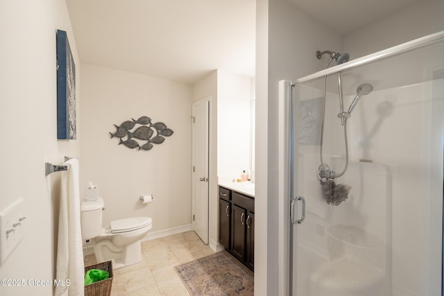 bathroom with a shower stall, toilet, vanity, and baseboards