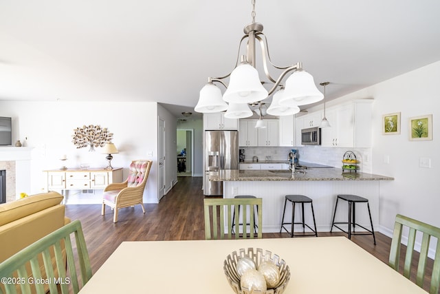 kitchen with stainless steel appliances, backsplash, dark wood finished floors, stone counters, and white cabinetry