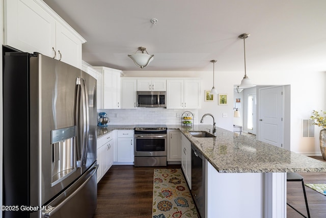 kitchen featuring appliances with stainless steel finishes, a peninsula, a sink, and white cabinetry