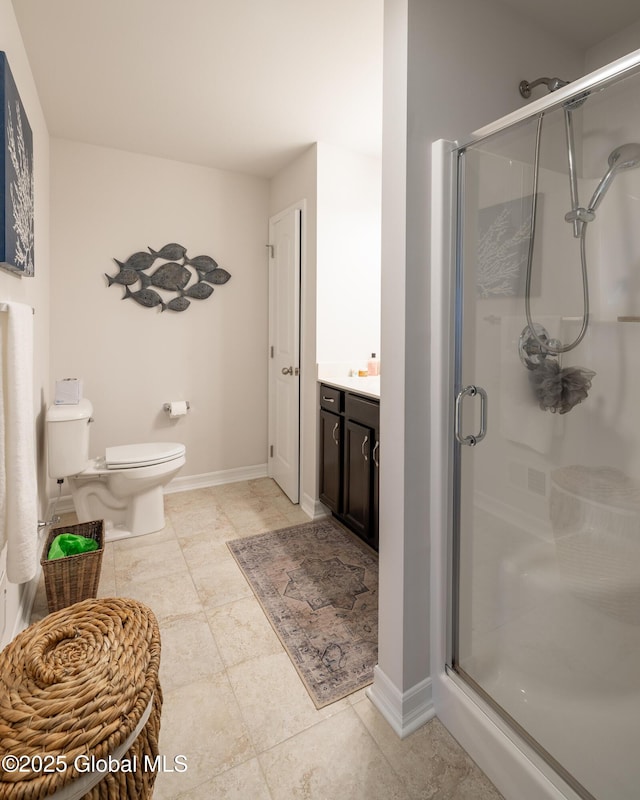 bathroom with a shower stall, toilet, baseboards, and vanity