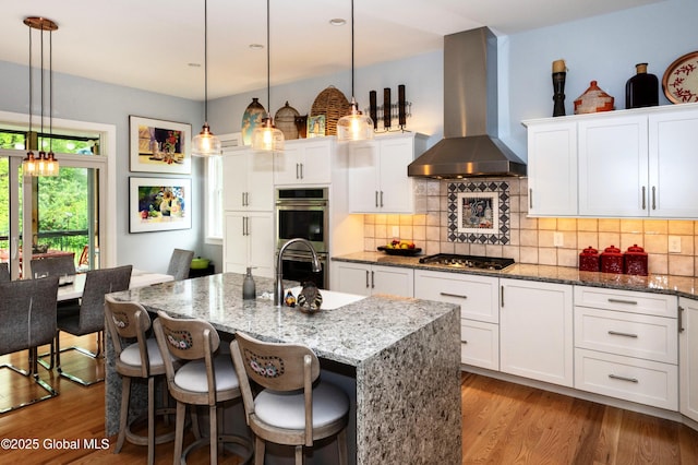 49 N Village Cir, Round Lake, NY 12151 - kitchen with wall chimney exhaust hood, a sink, stainless steel appliances, wood finished floors, and white cabinetry