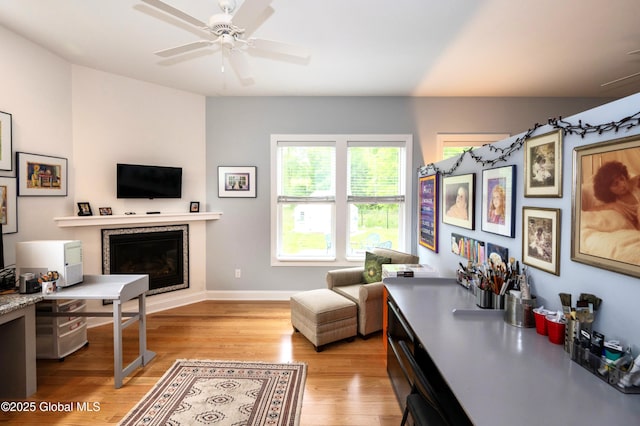49 N Village Cir, Round Lake, NY 12151 - living room with light wood finished floors, a glass covered fireplace, a ceiling fan, and baseboards