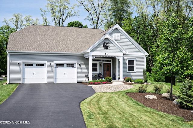 49 N Village Cir, Round Lake, NY 12151 - view of front facade featuring covered porch, an attached garage, asphalt driveway, a front lawn, and roof with shingles