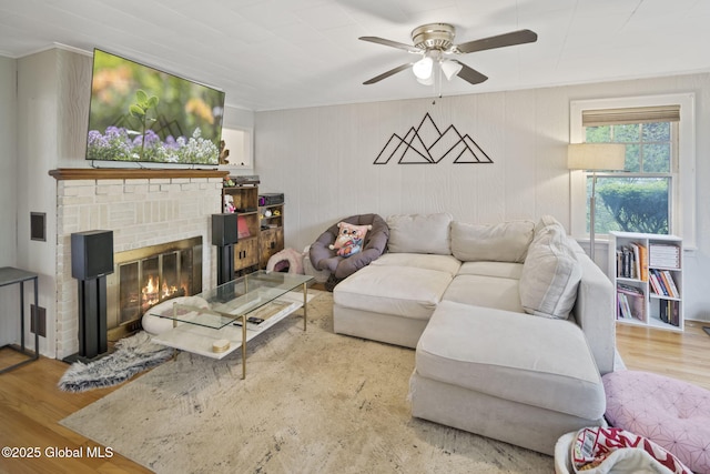 living room with ornamental molding, wood finished floors, ceiling fan, and a fireplace