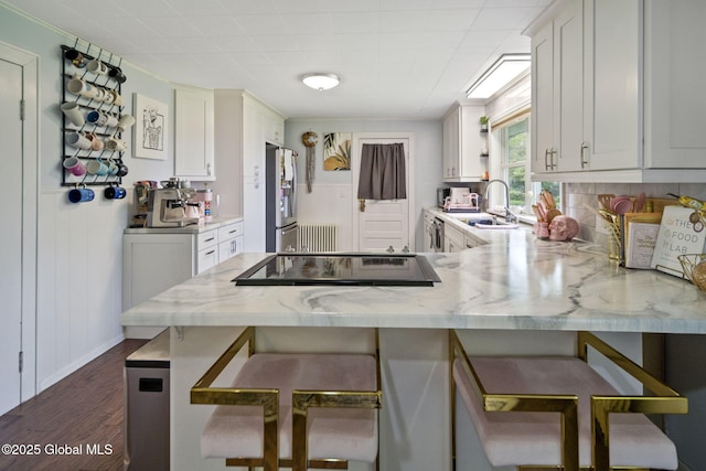 kitchen featuring a sink, stainless steel fridge with ice dispenser, a peninsula, cooktop, and dark wood-style floors