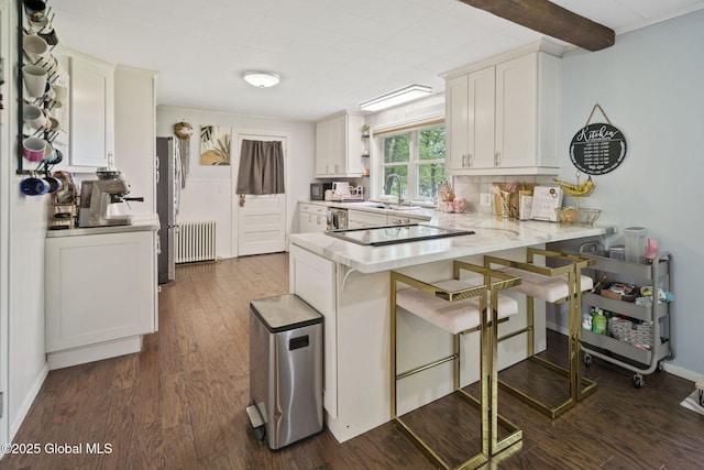 kitchen with radiator heating unit, a peninsula, black electric cooktop, dark wood-style floors, and a sink