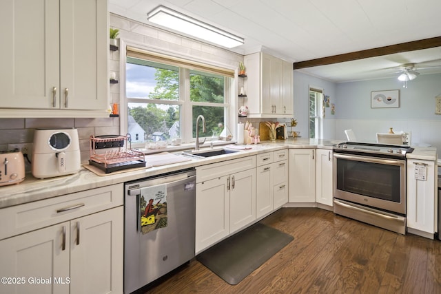 kitchen with appliances with stainless steel finishes, a sink, light countertops, beam ceiling, and dark wood finished floors