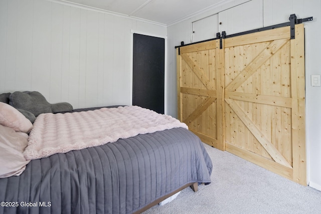 carpeted bedroom with a barn door and crown molding