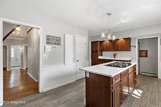 kitchen featuring gas stovetop, light wood-type flooring, light countertops, baseboard heating, and pendant lighting